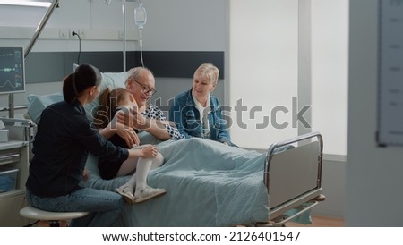 Child hugging sick grandpa in hospital ward bed at visit, comforting aged patient with illness. Kid and mother visiting senior man with IV drip bag and nasal oxygen tube. Visitors at clinic Royalty-Free Stock Photo #2126401547
