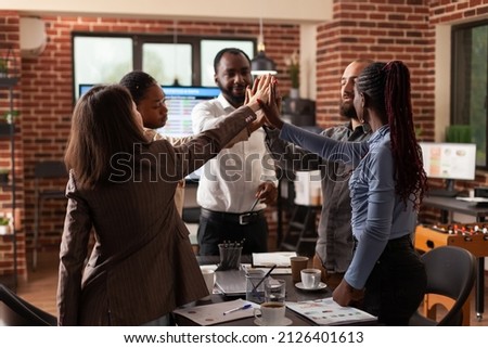 Happy excited businessteam rising hands celebrating business achievement winning management partnership enjoying successful collaboration in startup office. Diverse businesspeople at workplace Royalty-Free Stock Photo #2126401613