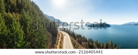 Aerial Panoramic View of Sea to Sky Highway on Pacific Ocean West Coast. Sunny Winter Day. Located in Howe Sound between Vancouver and Squamish, British Columbia, Canada. Royalty-Free Stock Photo #2126405441