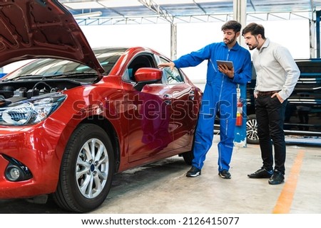 Mechanic man shows the car report on a digital tablet to the Middle East customer at the garage, A mechanic and a customer discussing repairs problems to his vehicle. Royalty-Free Stock Photo #2126415077