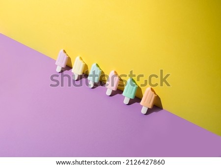 Ice cream sticks on pastel colors background. Trendy sunlight Summer made with popsicle ice cream on bright light background. Minimal summer concept.
