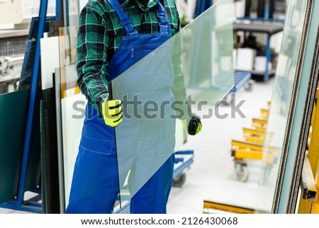 The glazier carries a pane of glass in his hands, the Glass Factory  Royalty-Free Stock Photo #2126430068