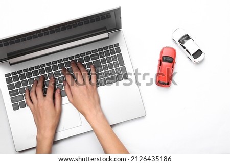 Hands are typing on a laptop keyboard, and toy cars on a white background. Search auto concept Royalty-Free Stock Photo #2126435186