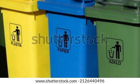 Three garbage containers for garbage segregation, close up —yellow "plastic", blue "paper", green "glass". Colored designations of garbage containers for different types of waste. Royalty-Free Stock Photo #2126440496