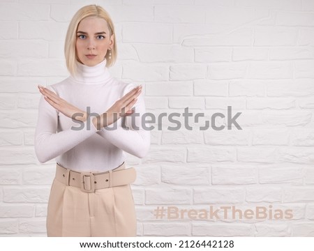 Break the bias symbol of woman's international day. The arms of a girl in white are crossed on a white brick wall. Woman arms crossed to show solidarity, breaking stereotypes, inequality
 Royalty-Free Stock Photo #2126442128