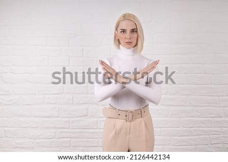 Break the bias symbol of woman's international day. The arms of a girl in white are crossed on a white brick wall. Woman arms crossed to show solidarity, breaking stereotypes, inequality
 Royalty-Free Stock Photo #2126442134