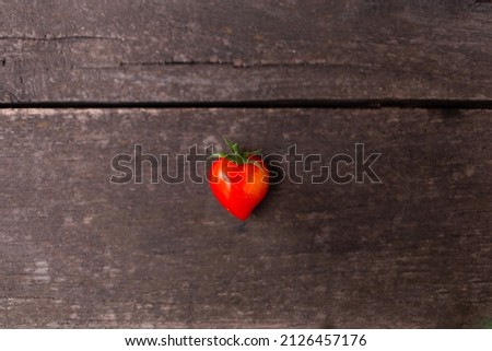 Heart shaped freshly picked tomato on the wooden background. Love concept