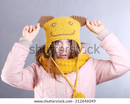 beautiful cheerful girl in the yellow hat. Fashion portrait on gray background. Autumn clothing