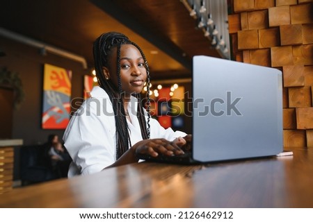 Happy african american woman worker using laptop work study at computer in loft office or cafe, smiling mixed race female student freelancer using pc app dating communicating online watching webinar