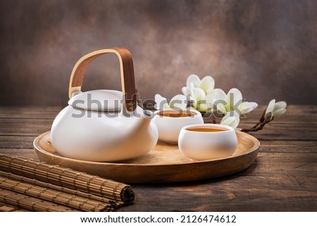 Tea concept with white tea set of cups and teapot with fresh tea on wooden background with copy space.  Royalty-Free Stock Photo #2126474612