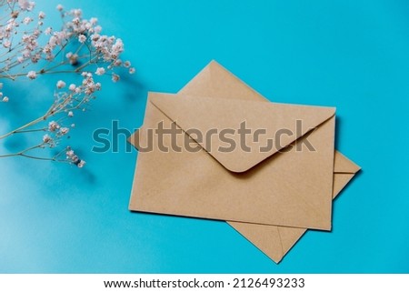 Brown craft envelope and spring flowers on blue background. Blank for for mockup design, letter, postcard. Flat lay. Top view.