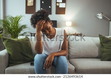 Young attractive African American woman lying at home living room couch feeling sad tired and worried suffering depression in mental health, problems and broken heart concept.