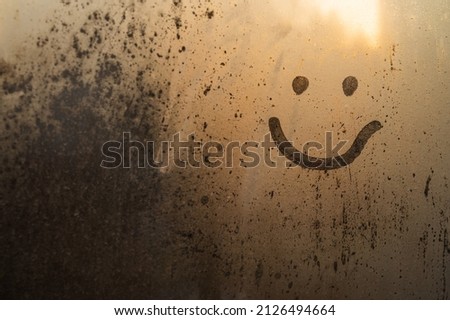 Cute smiley, smiling, painted on the window, dew and drops of water, rain, morning in the warm rays, happy when his rainy weather is a beautiful art. Place for inscription. Selective focus