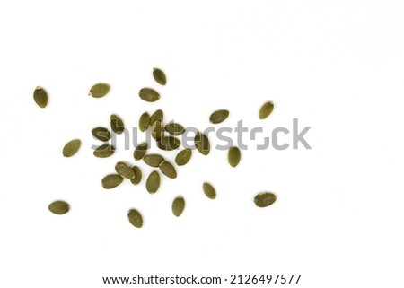 heap of green pumpkin seeds isolated on white background, scattered raw peeled seeds, top view