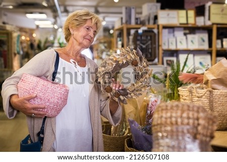 Portrait of senior woman choosing various household goods in good store