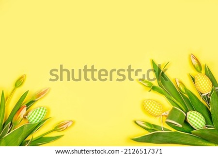 Easter hand made eggs with white tender tulips on a yellow background. Easter decorative elements.Background for greeting holiday card for Easter.Spring decorative elements and flowers.Spring meeting. Royalty-Free Stock Photo #2126517371