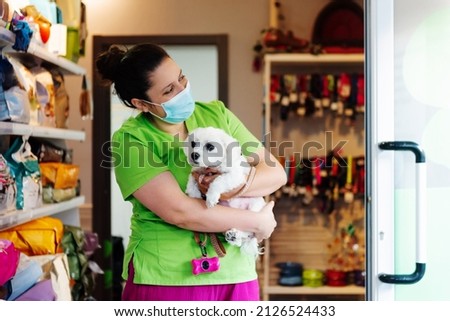 Veterinary woman in a medical mask holding a small white dog without breed in her arms. pet healthcare.