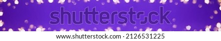 Banner of Christmas bright gold colors bokeh different sizes around the frame on vibrant purple blurred background. Holiday template and shiny greeting concept with copy space