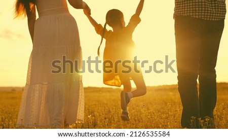 mother father holding small child by hand sunset. silhouette small child with parents sun. happy family nature. mom dad and child are walking park. happy family travel sunset together. dream childhood