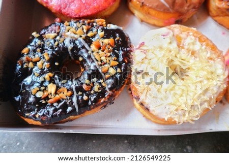 Donuts with chocolate, peanut, and cheese flavors in box packaging