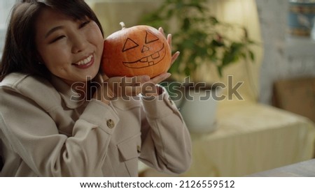 A beautiful woman with long hair is showing her drawing halloween pumpkin