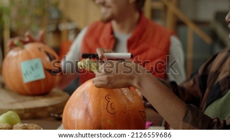 Friends stick name stickers on Halloween pumpkins