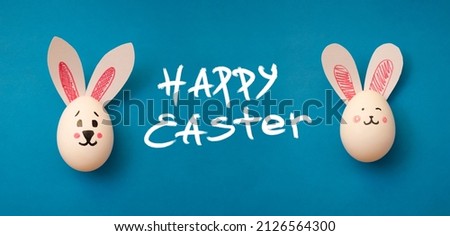 Food photo for Easter holiday. Chicken eggs with cute rabbit faces and bunny ears on a blue background. Easter coloring book for kids. Greeting card. Text Happy Easter. Copyspace. Banner. Handwritten