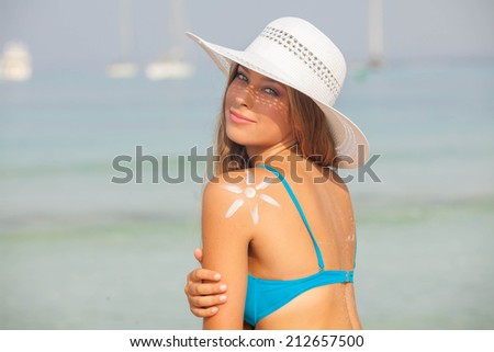 concept for safe sunbathing, woman with sun cream and hat