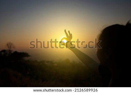 Silhouette of woman hands ok sign with sunset light.