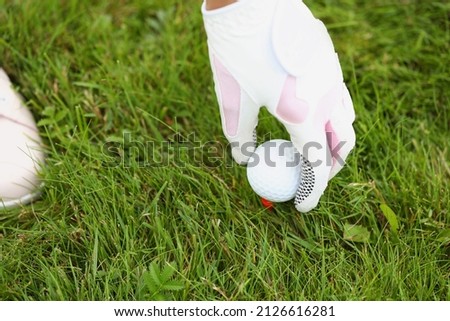 Close-up of person picking up golf ball. White and pink protective glove on player. Equipment for correct game or competition. Luxury type of sport and active lifestyle concept