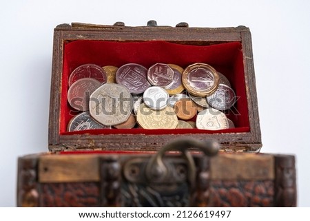 a small old wooden chest with coins on a white background. savings