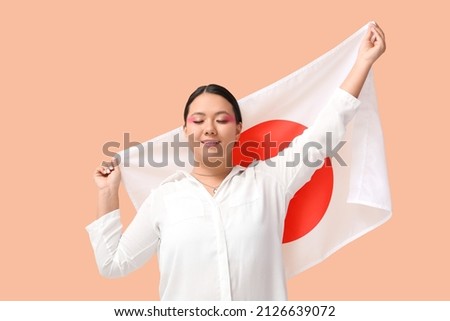 Beautiful young Asian woman with flag of Japan on color background