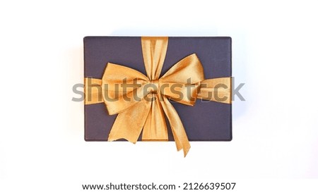Man's hand holding a black gift box with a gold ribbon on a white background. Valentine concept, Christmas and Newyear concept. Anniversary and Thanksgiving concept.