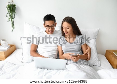 Young couple using laptop in bed