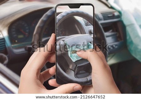 The girl takes a picture of the airbag on the steering wheel of the car at the scene of the accident on a smartphone to receive insurance compensation. Selective focus. 
