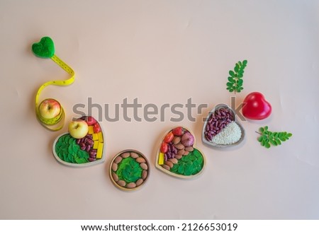 Organic  healthy  food  in  wooden  bowls ,yellow  tape  measure  wrapped around an  apple an  two  heart  shape  on  pastel  background  for  the health  concept