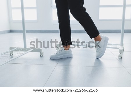 Women's legs in black trousers and white leather sneakers. Modern casual style. New shoe collection