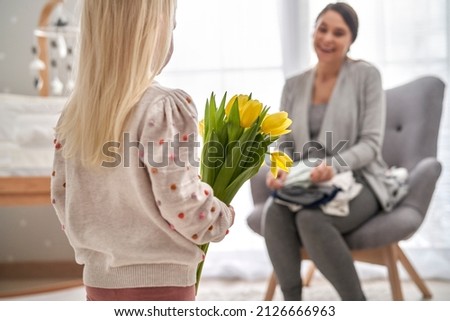Elementary age girl about to hand in flowers to her mother on mother's day