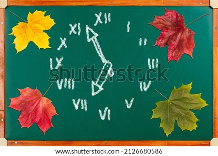 School board with colorful autumn maple leaves and clock drawn in chalk