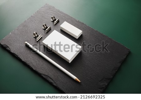 Blank business card, pencil, eraser and clips on stone board.