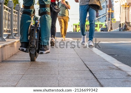 Rider's legs in protective gear on an electric unicycle (EUC). Driving around the city on an electric monowheel. Royalty-Free Stock Photo #2126699342