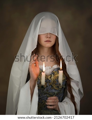 A girl with a face covered with a thin translucent scarf and two candles