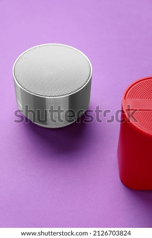 Modern wireless portable speakers on purple background, closeup