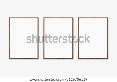 Three vertical picture frame mockup on a wall. Artwork template isolated Royalty-Free Stock Photo #2126706119