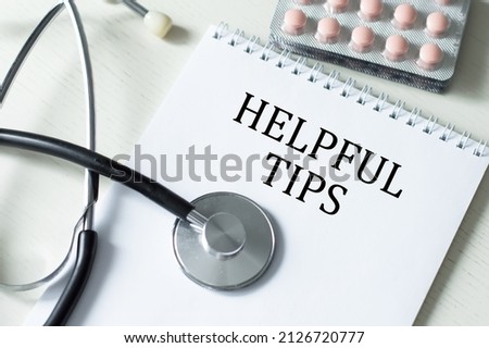 text HELPFUL TIPS on a notepad on the medical table. business and education concept