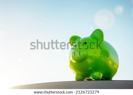 Green piggy bank against blue sky background concept for saving, accounting, banking and business account or sustainable and environmentally friendly finance Royalty-Free Stock Photo #2126723279