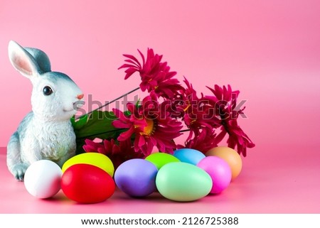 rabbit bouquet of flowers and painted multicolored easter eggs on a pink background. High quality photo