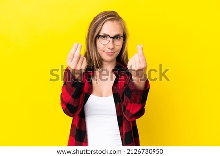 Young English woman isolated on yellow background making money gesture