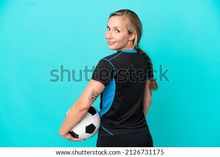 Young English woman isolated on blue background with soccer ball