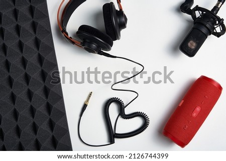 Microphone, headphones and portable stereo speaker on on white background with copy space and acoustic foam panel